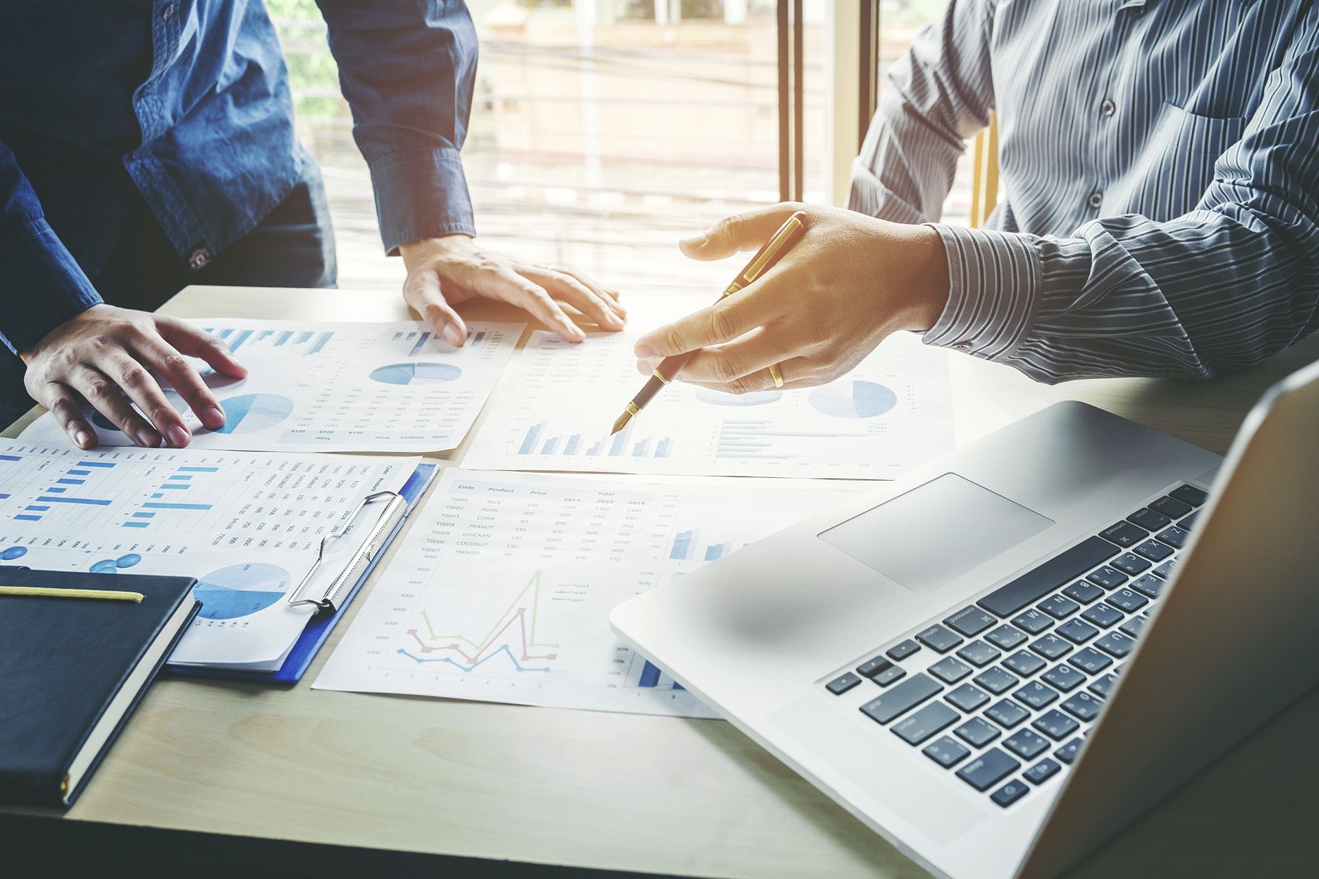 Poslovni sestanek ob finančnih poročilih, grafih in prenosnem računalniku